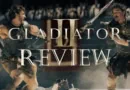 gladiator-2-review-banner warriors fighting in background Paul Mescal and Pedro Pascal