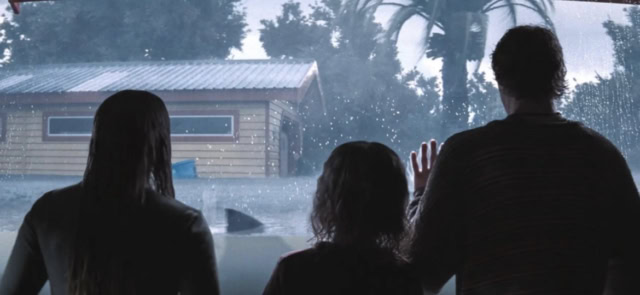 3 people watch from inside a house as a shark swims by in a flood in the 2026 movie Thrash