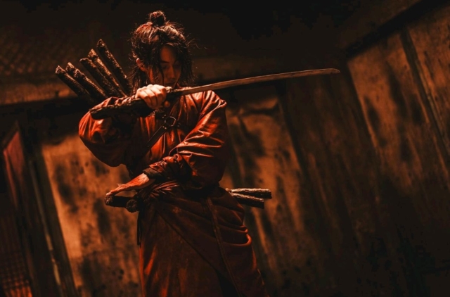 Person in costume wielding a sword in a dark, atmospheric setting. Nam Joo-hyuk in Netflix series The East Palace