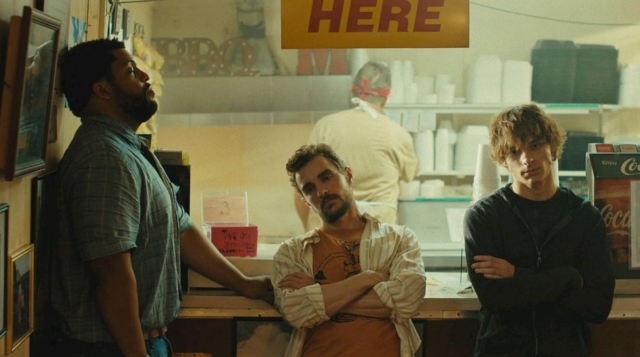 Three young men standing inside a fast food restaurant, one leaning on the counter. Dave Franco, O'Shea Jackson Jr., and Mason Thames in the 2026 film Idiots
