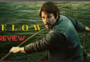 Josh Hartnet in Below, movie review banner. A man on a boat holding a fishing net in a green water setting.