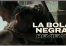 La Bola Negra movie review still with two men embracing in dim light.