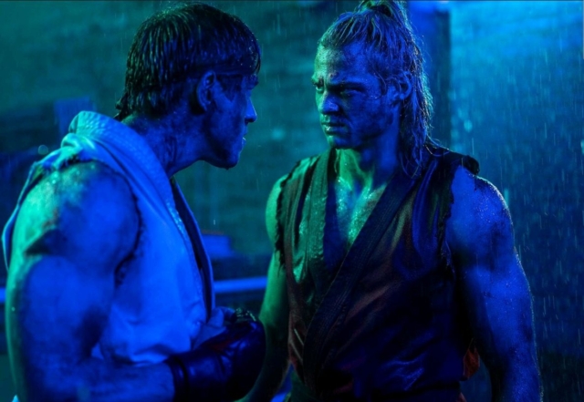 Two fighters face off in a rain-soaked scene, intense confrontation. Noah Centineo and Andrew Koji in the film Street Fighter